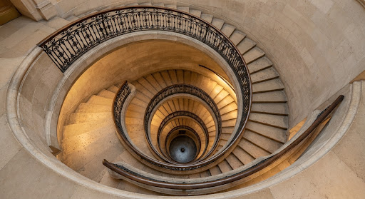 Top-down view of a grand classical spiral stone staircase.